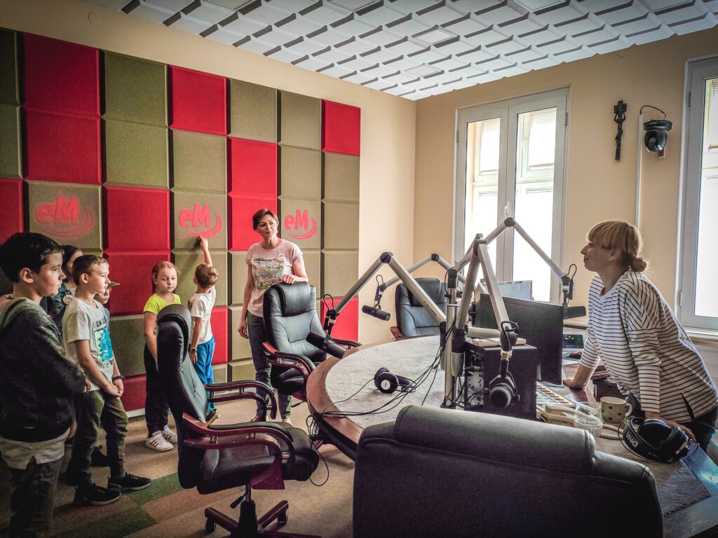 Zdjęcie. Grupa dzieci w studiu radiowym radia eM.