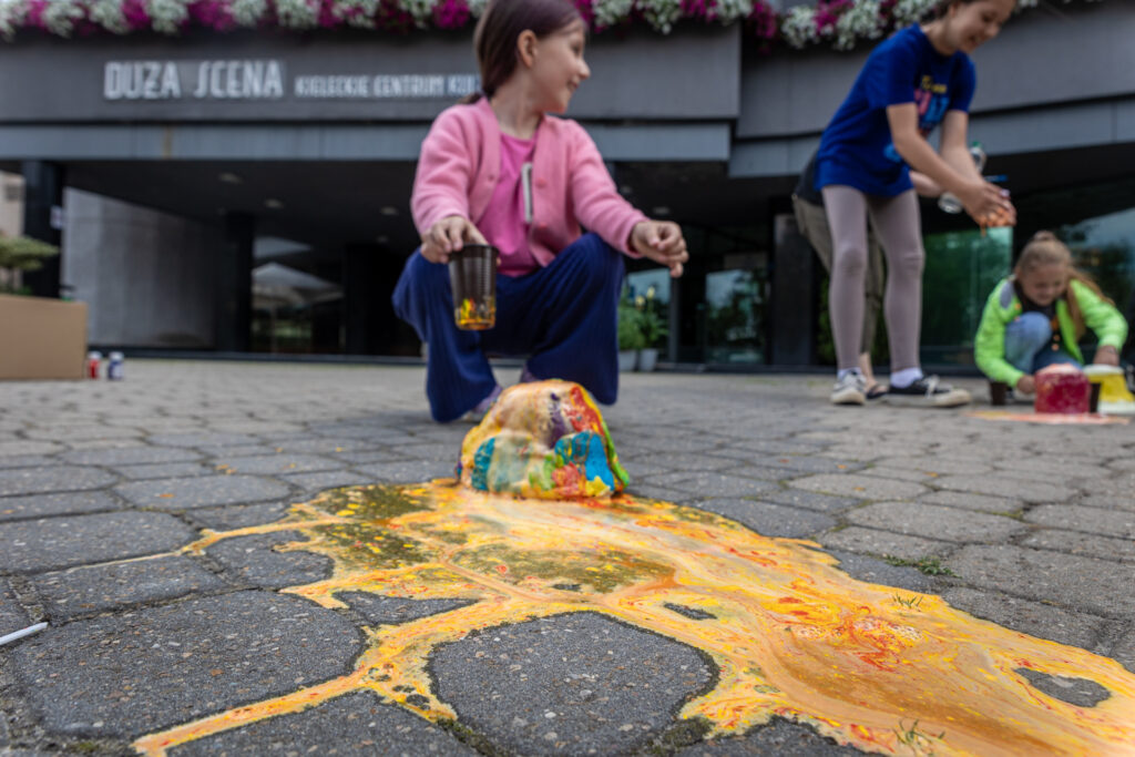 Zdjęcie. Kolorowy wulkan z wyciekającą z niego pomarańczowo-żółtą pianą.